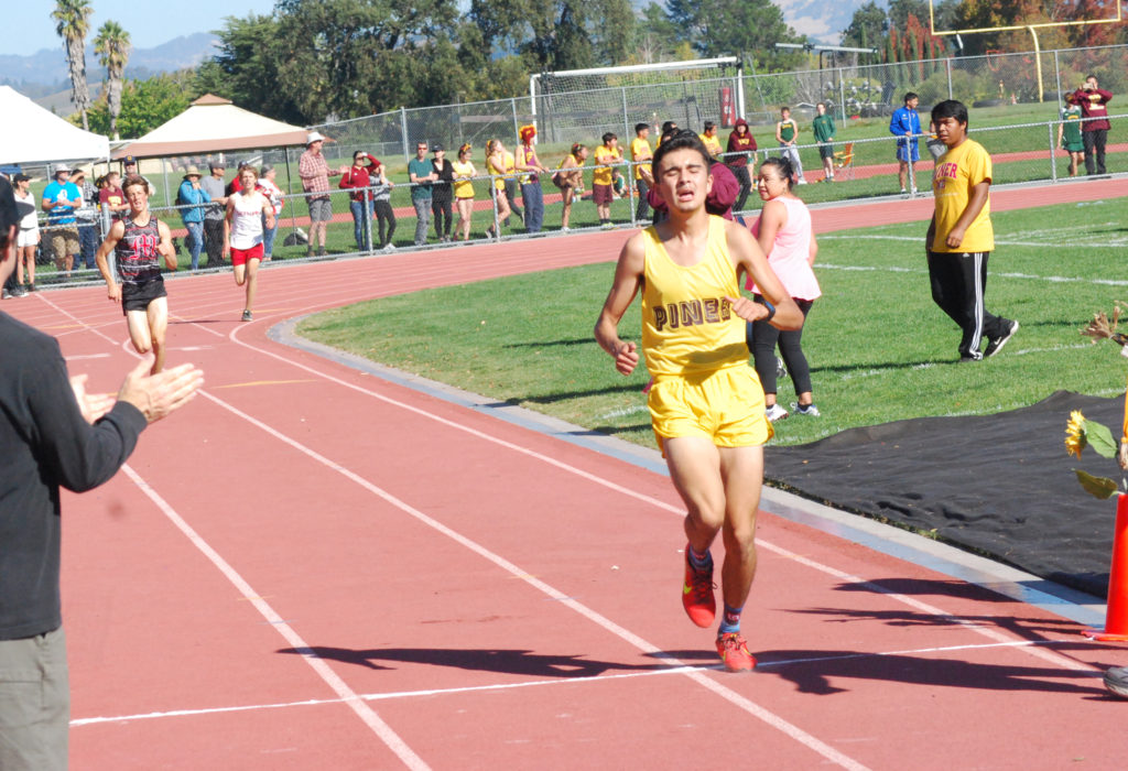 Athlete prepares for pole vault on a track with others watching.