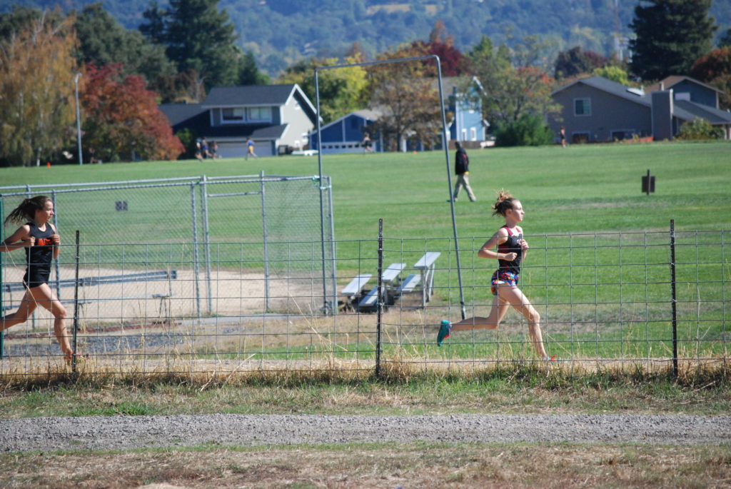 Athlete prepares for pole vault on a track with others watching.