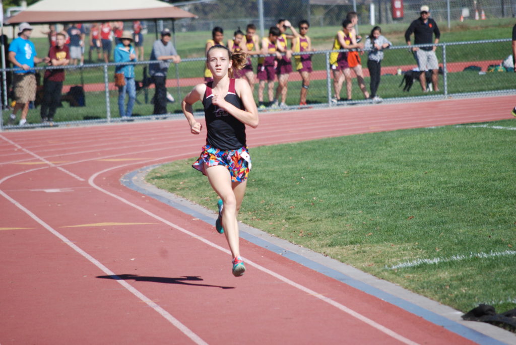 Athlete prepares for pole vault on a track with others watching.