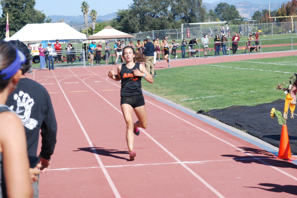 Athlete prepares for pole vault on a track with others watching.
