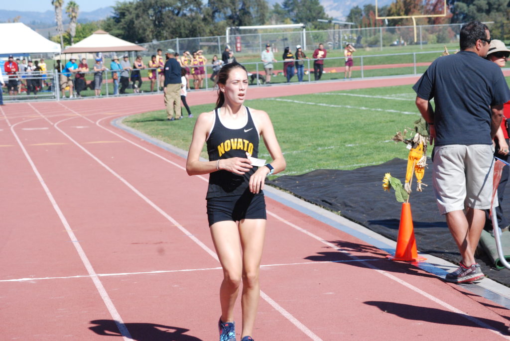 Athlete prepares for pole vault on a track with others watching.