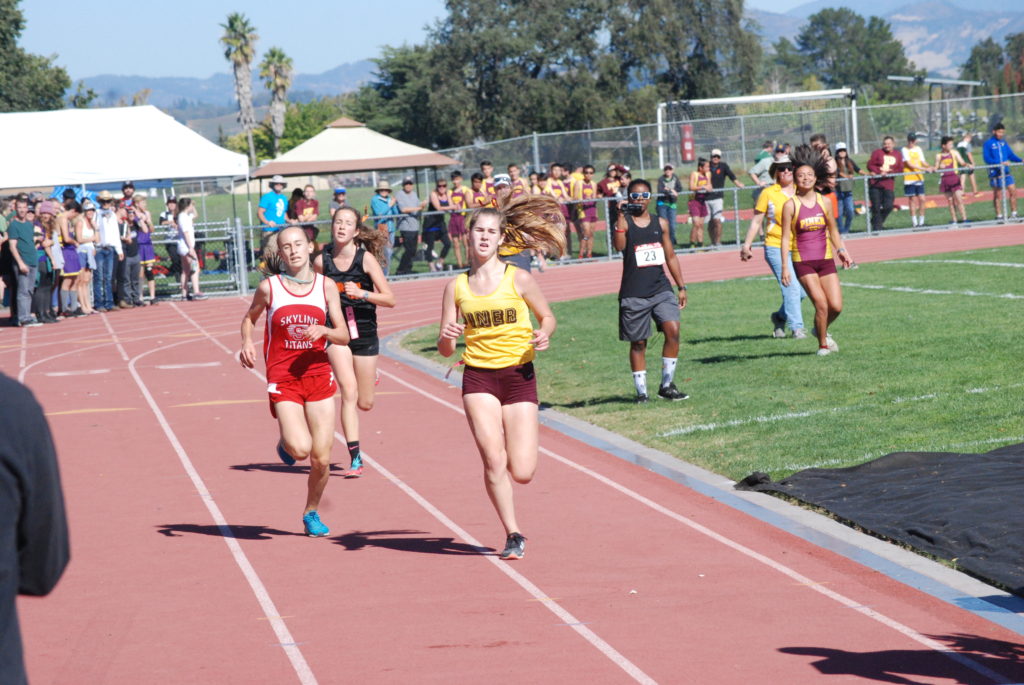 Athlete prepares for pole vault on a track with others watching.