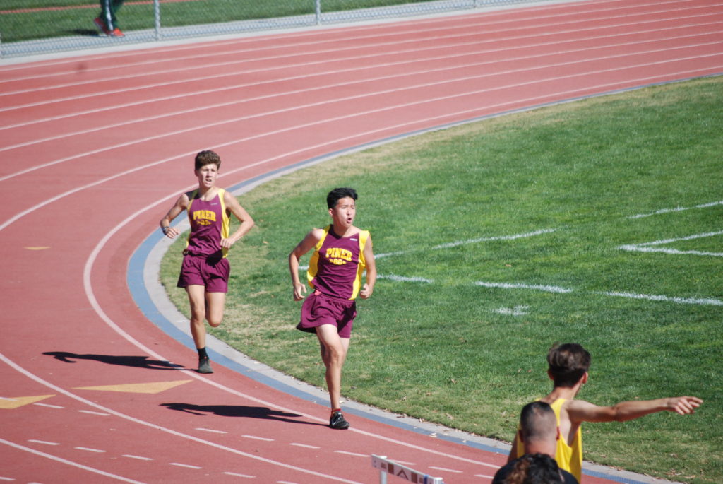 Athlete prepares for pole vault on a track with others watching.