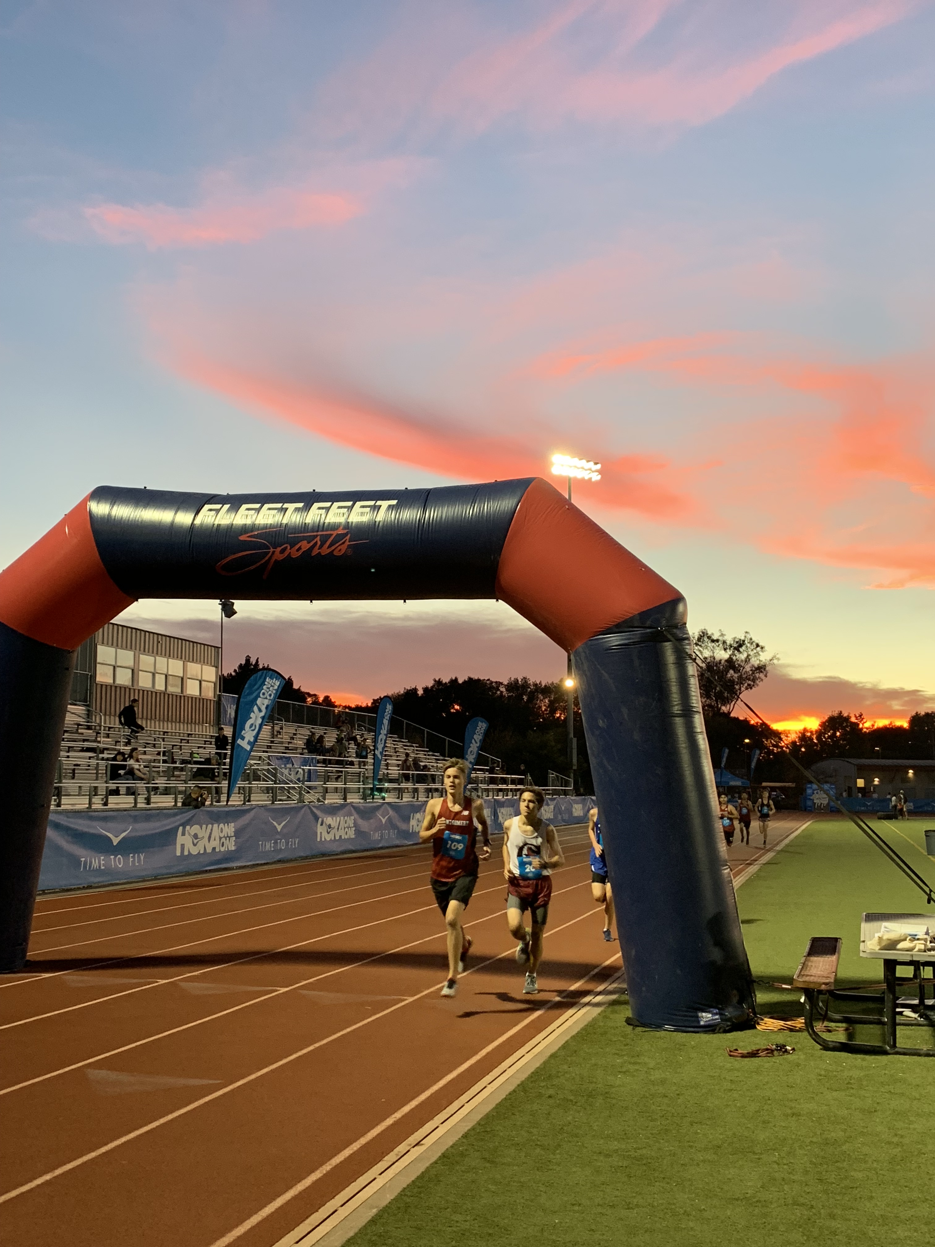 Athlete prepares for pole vault on a track with others watching.