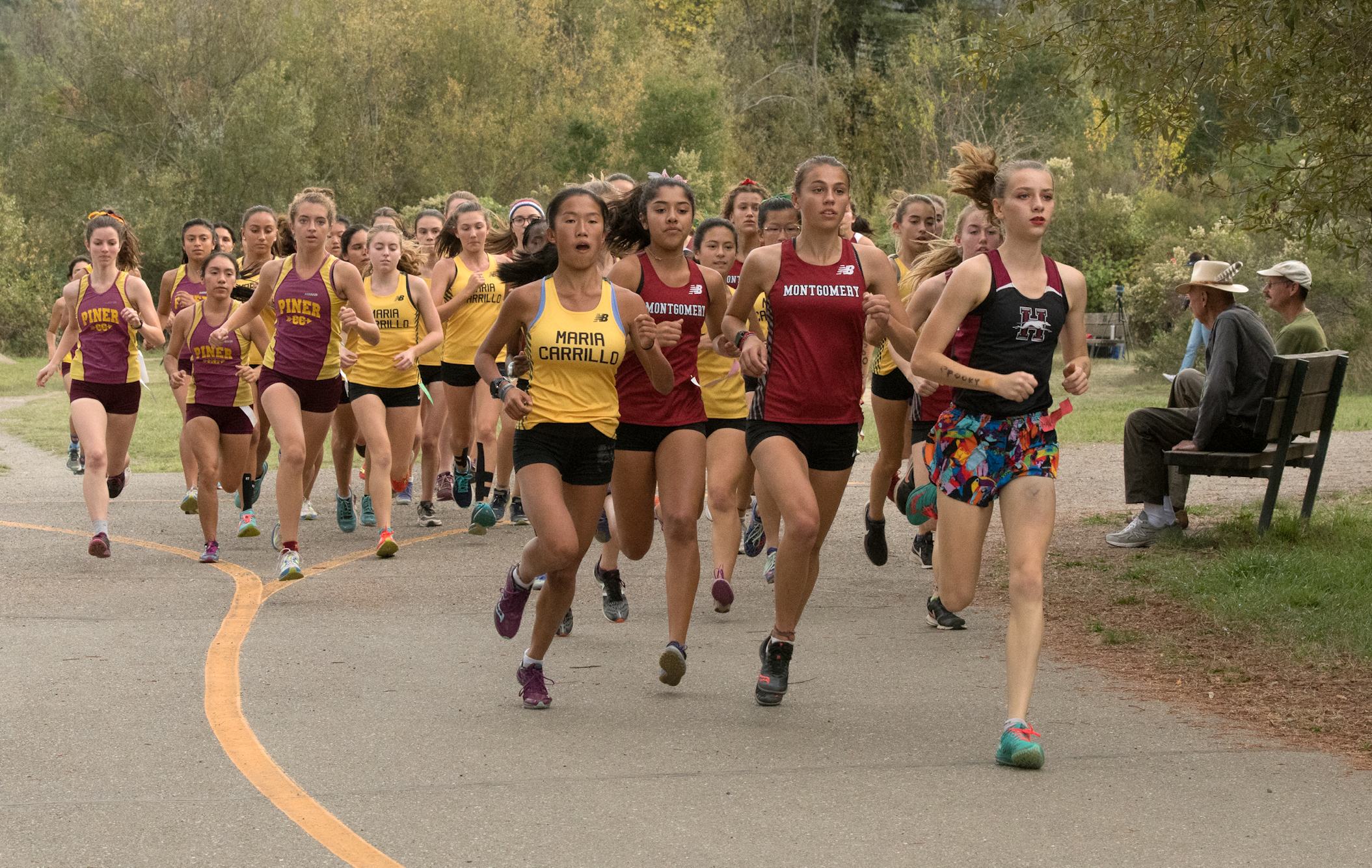 Athlete prepares for pole vault on a track with others watching.
