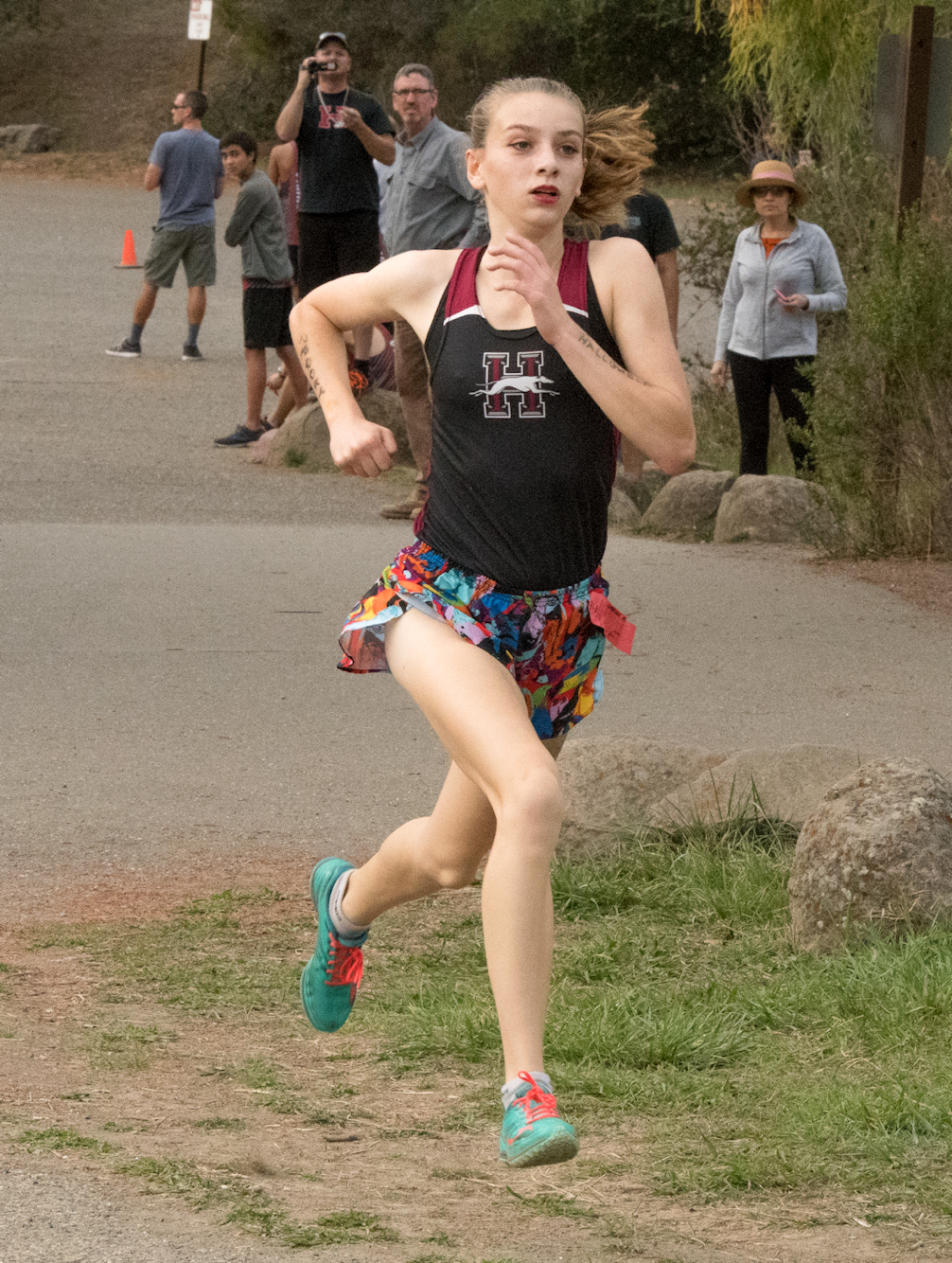 Athlete prepares for pole vault on a track with others watching.