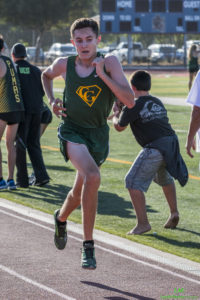Athlete prepares for pole vault on a track with others watching.