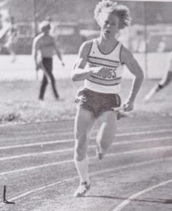 Athlete prepares for pole vault on a track with others watching.