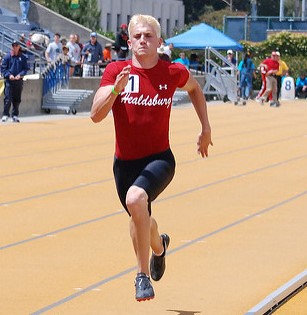Athlete prepares for pole vault on a track with others watching.