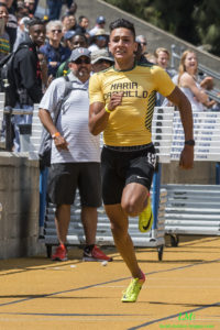 Athlete prepares for pole vault on a track with others watching.