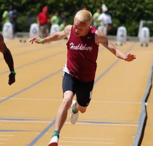 Athlete prepares for pole vault on a track with others watching.