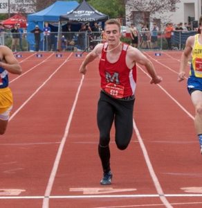 Athlete prepares for pole vault on a track with others watching.