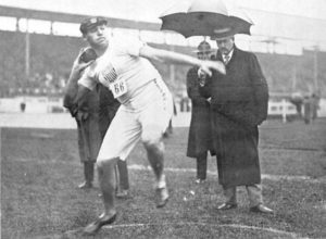 Athlete prepares for pole vault on a track with others watching.