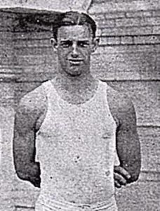 Athlete prepares for pole vault on a track with others watching.