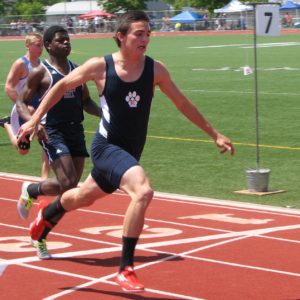 Athlete prepares for pole vault on a track with others watching.