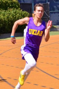 Athlete prepares for pole vault on a track with others watching.