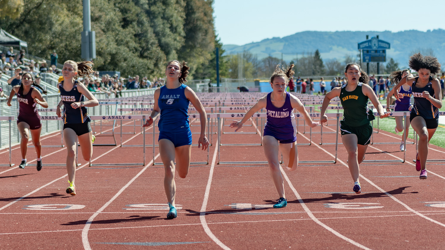 Athlete prepares for pole vault on a track with others watching.