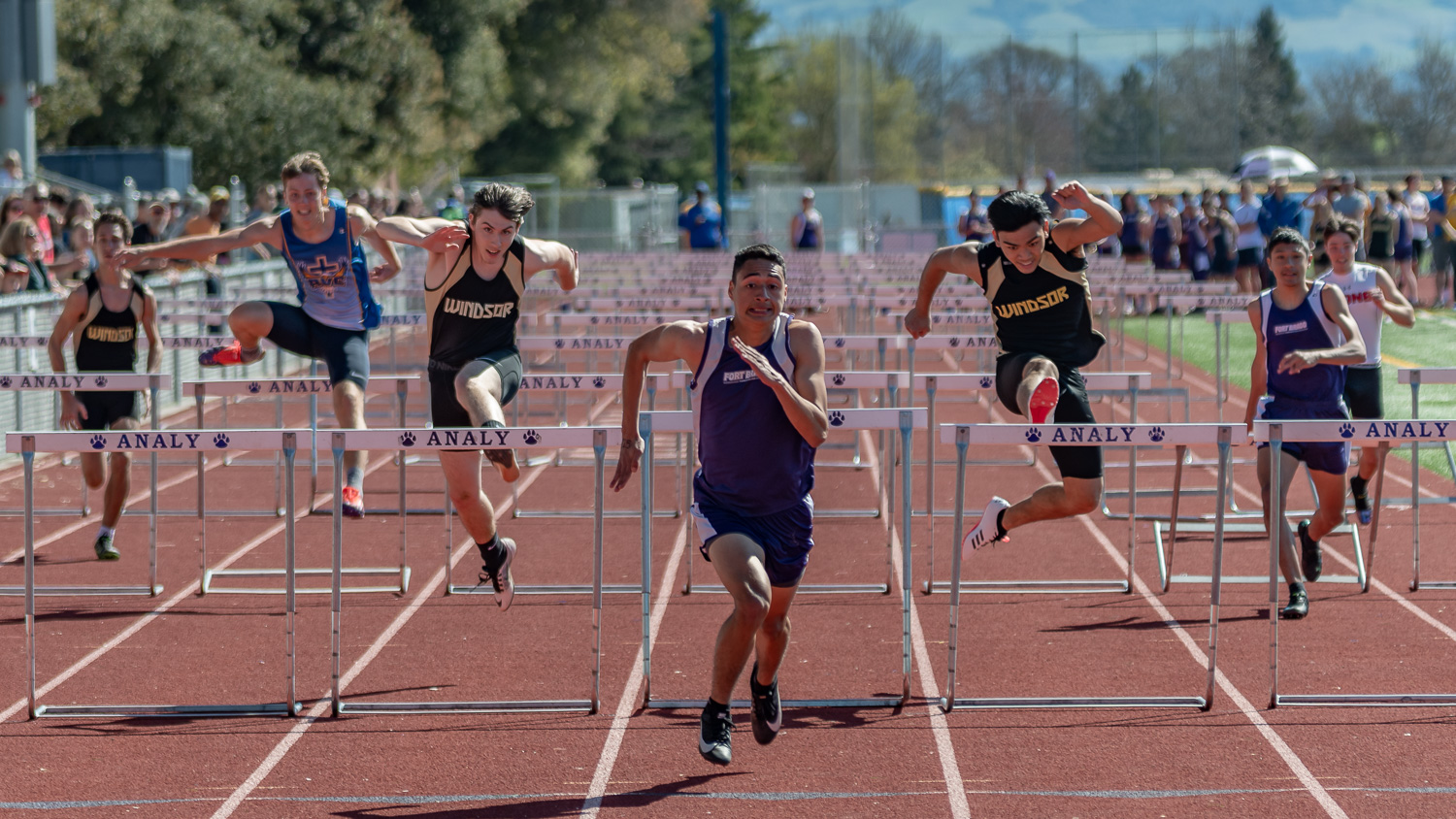 Athlete prepares for pole vault on a track with others watching.