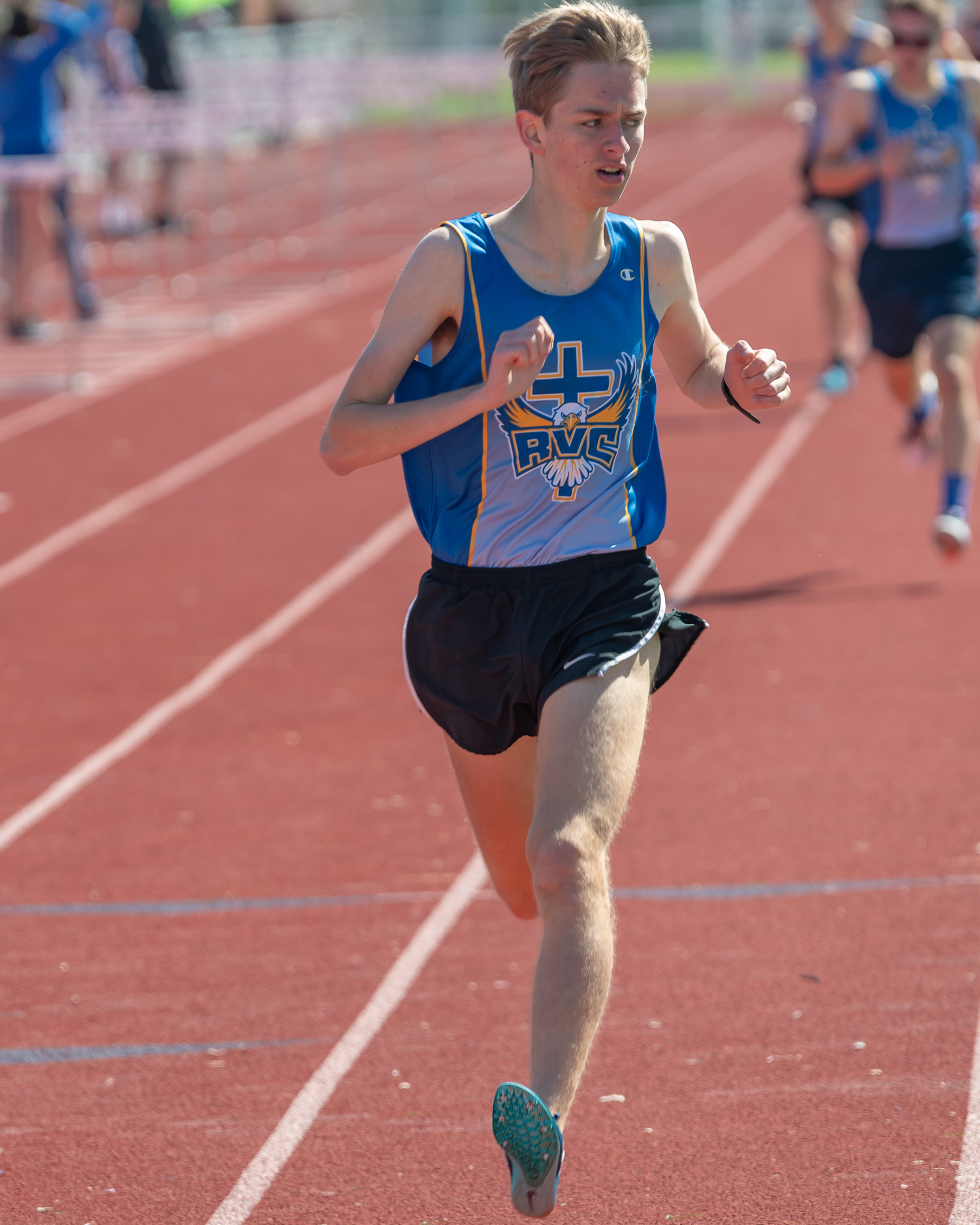Athlete prepares for pole vault on a track with others watching.
