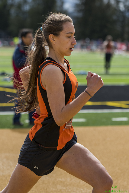 Athlete prepares for pole vault on a track with others watching.