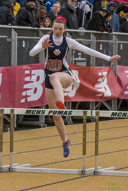 Athlete prepares for pole vault on a track with others watching.