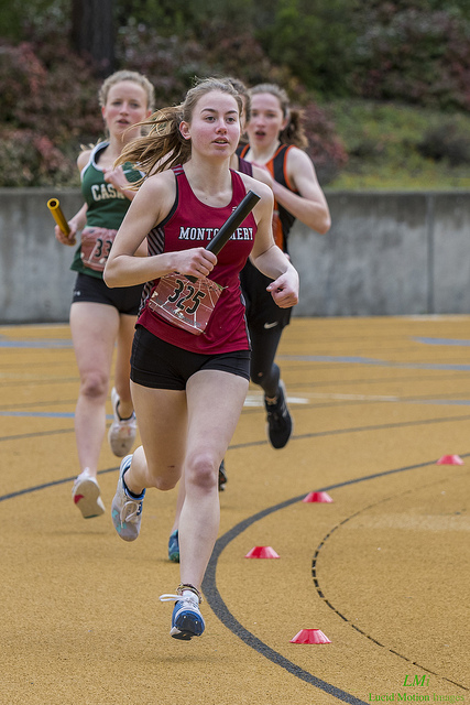 Athlete prepares for pole vault on a track with others watching.