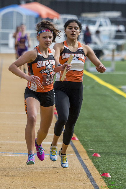 Athlete prepares for pole vault on a track with others watching.