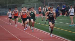 Athlete prepares for pole vault on a track with others watching.