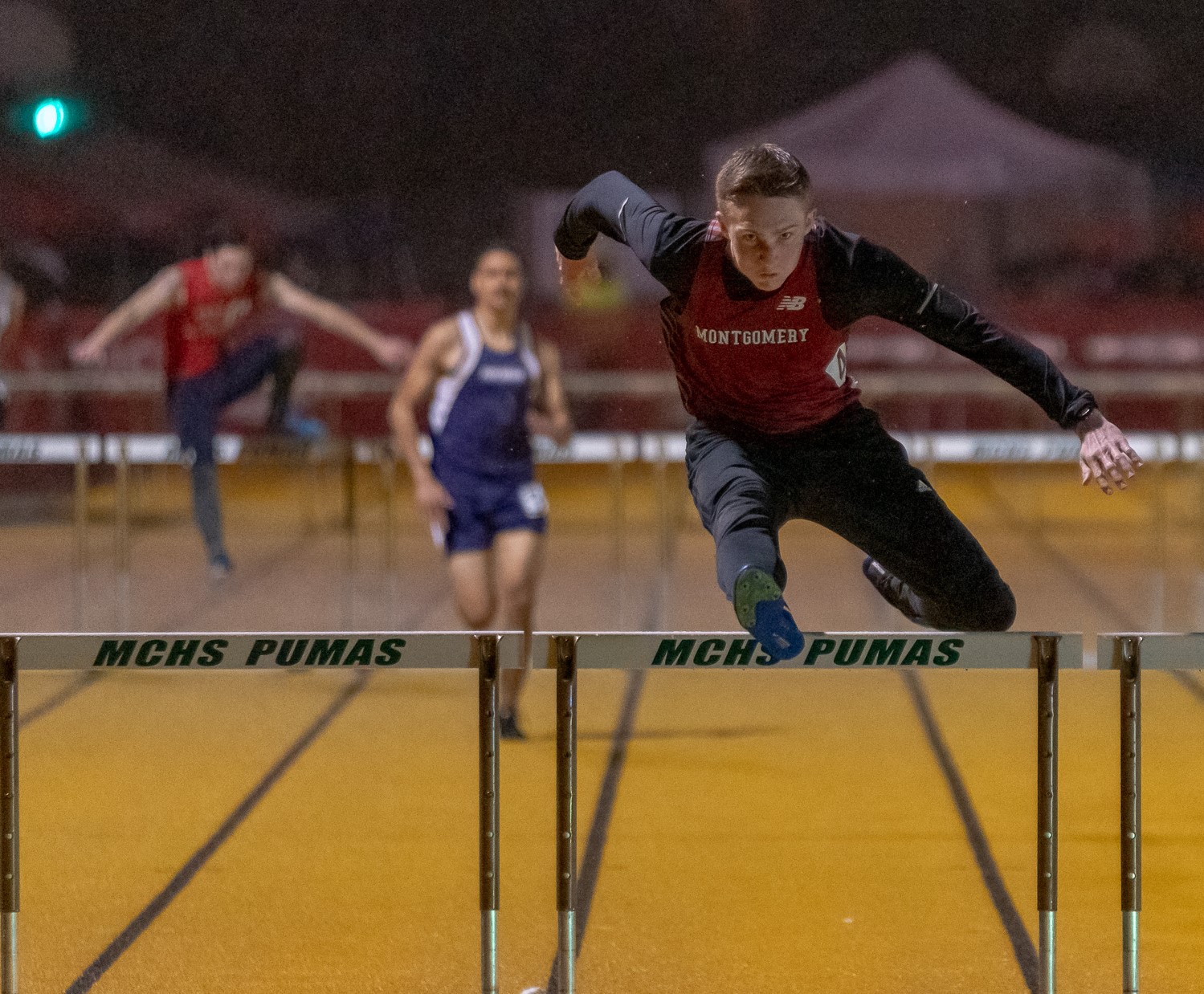 Athlete prepares for pole vault on a track with others watching.