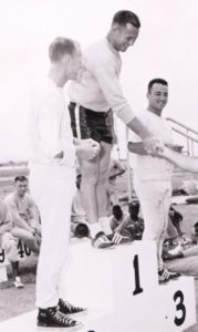 Athlete prepares for pole vault on a track with others watching.