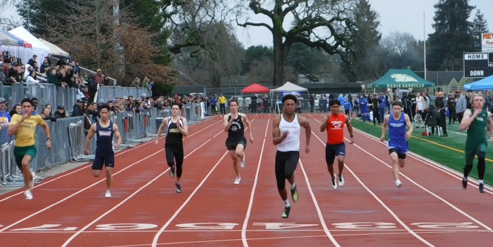 Athlete prepares for pole vault on a track with others watching.