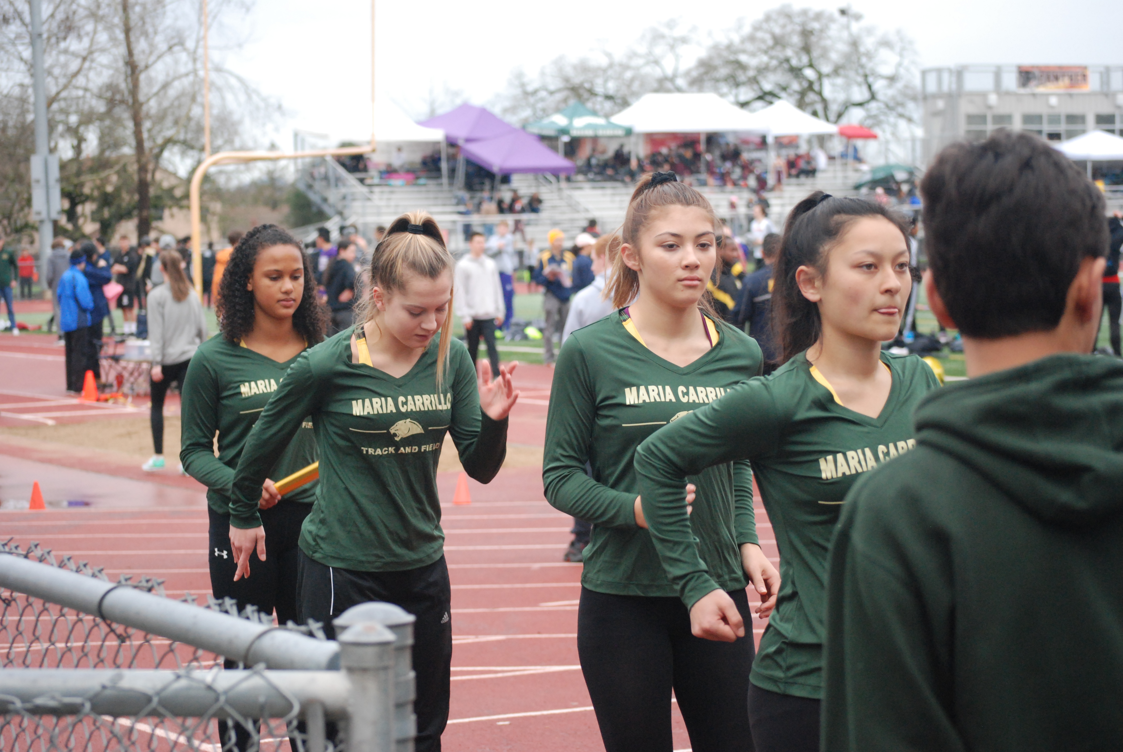 Athlete prepares for pole vault on a track with others watching.