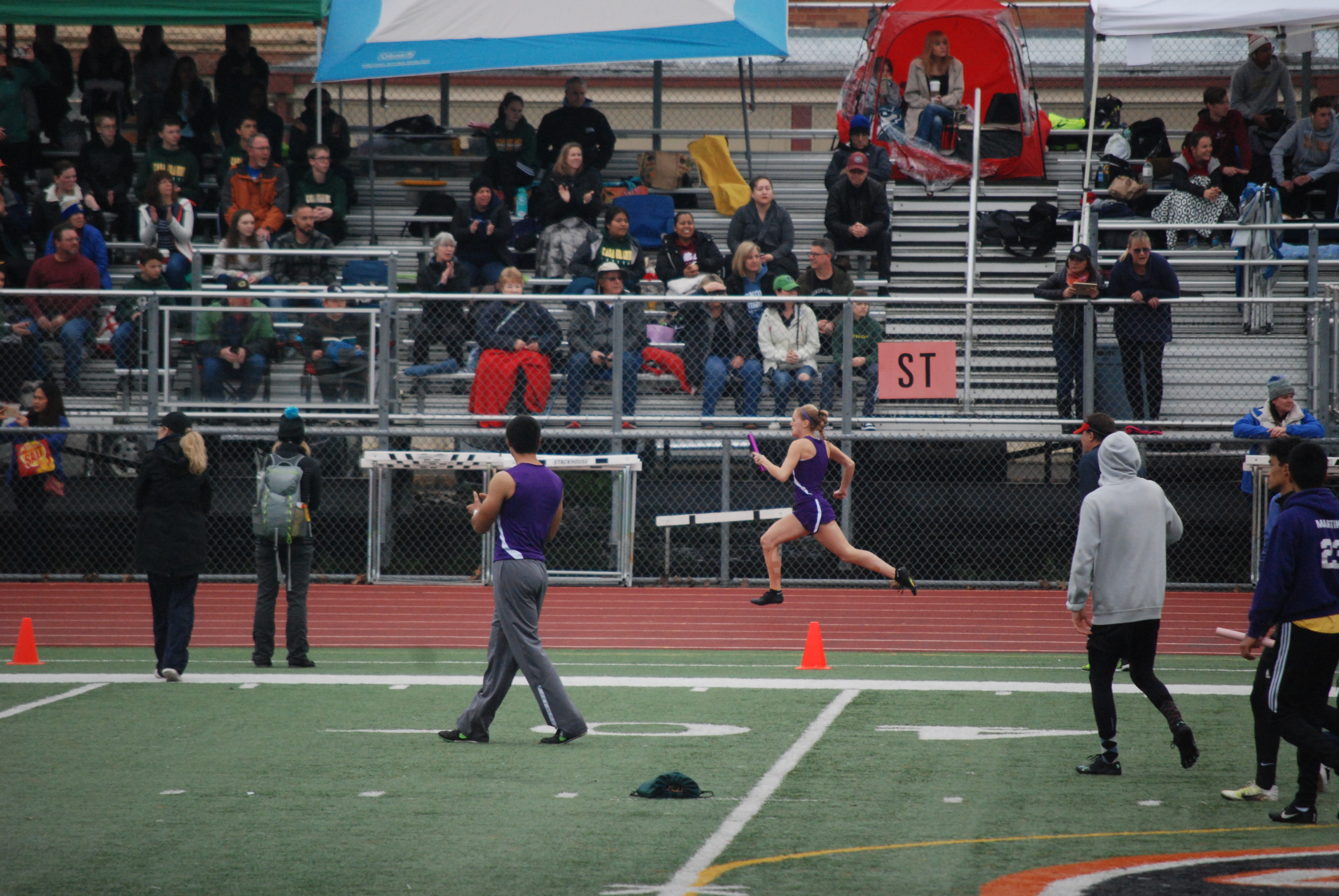 Athlete prepares for pole vault on a track with others watching.