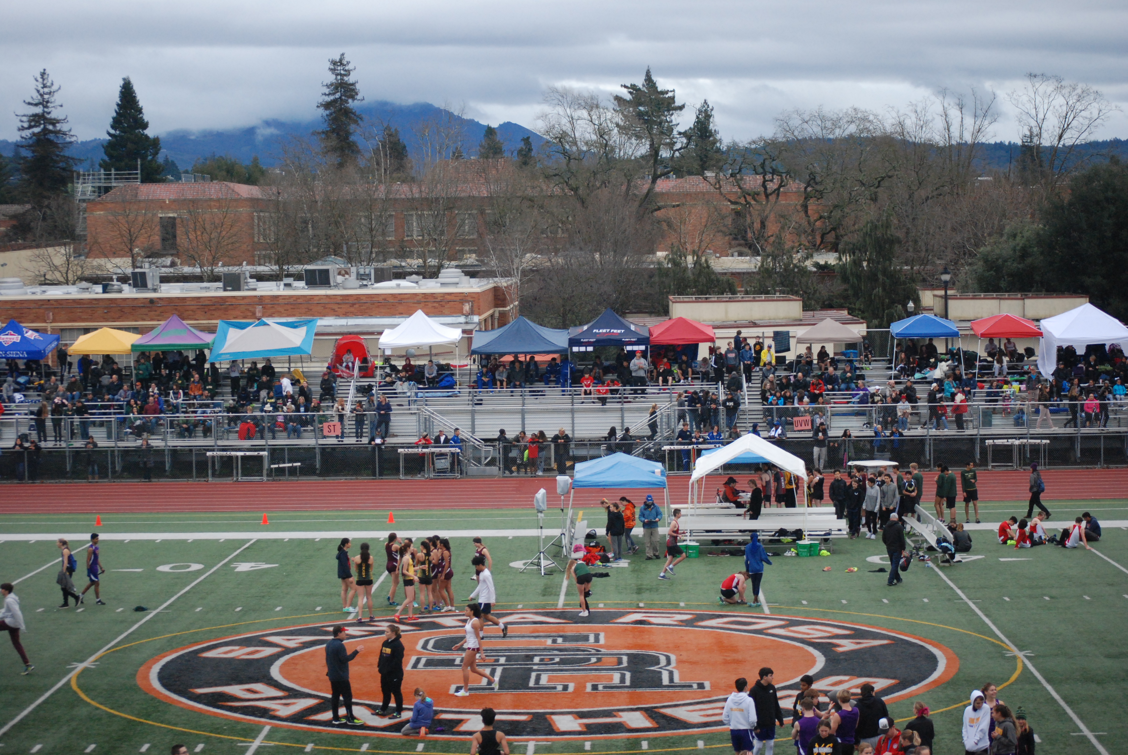 Athlete prepares for pole vault on a track with others watching.