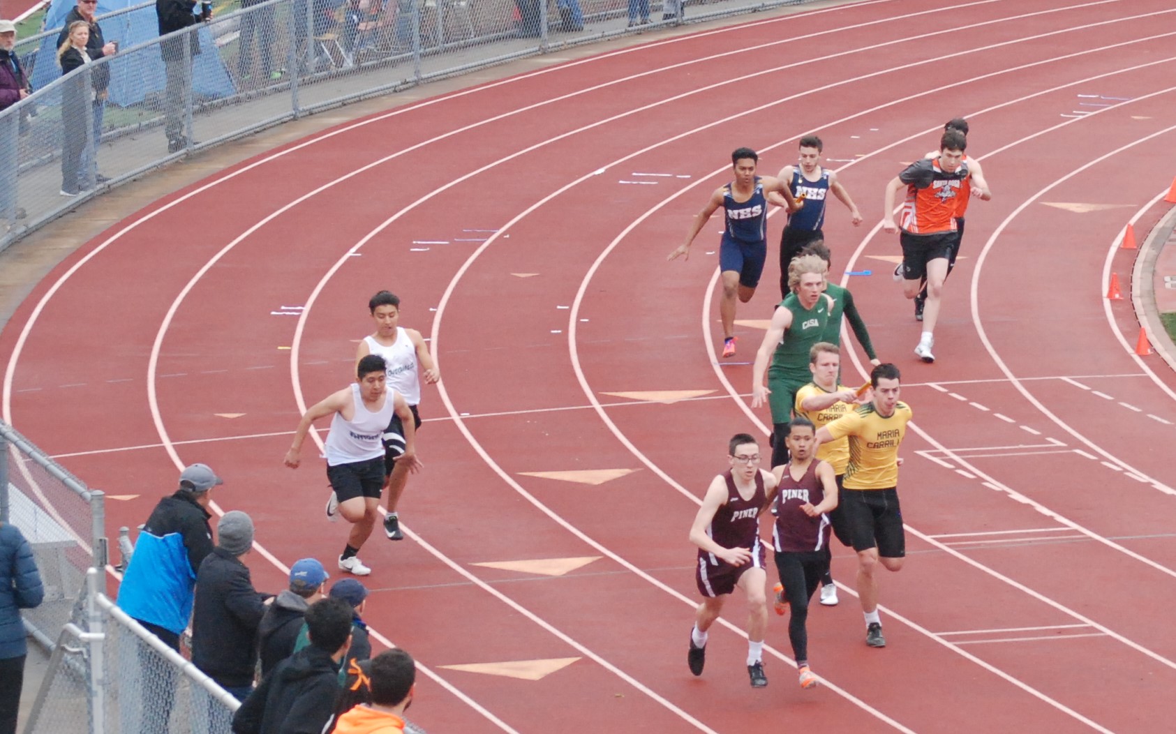 Athlete prepares for pole vault on a track with others watching.