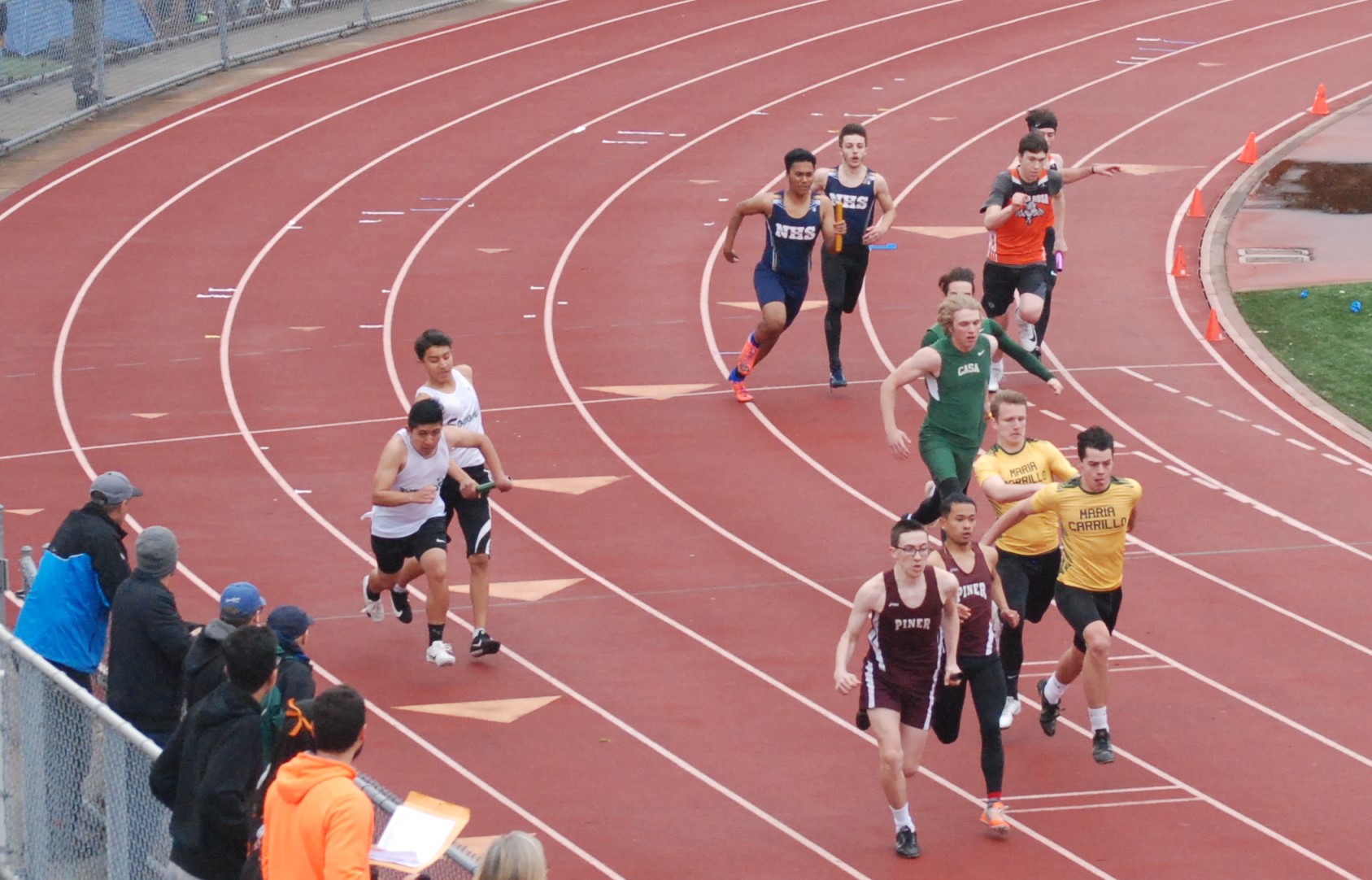 Athlete prepares for pole vault on a track with others watching.