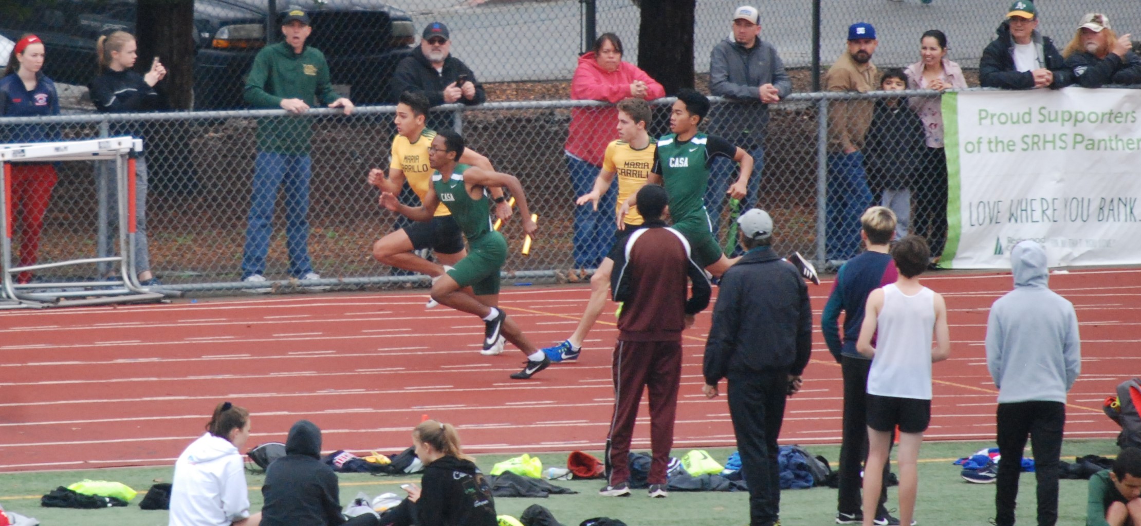 Athlete prepares for pole vault on a track with others watching.
