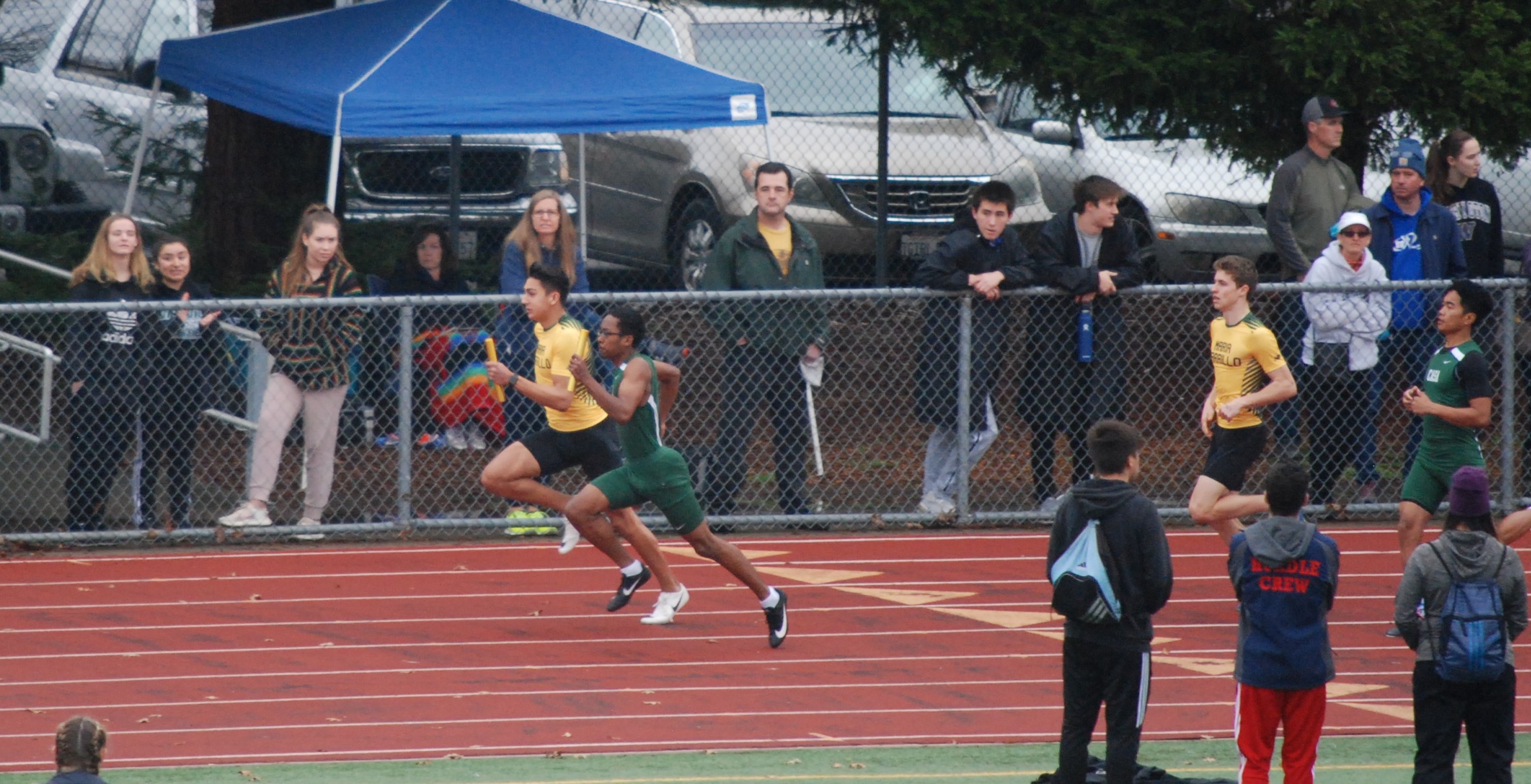 Athlete prepares for pole vault on a track with others watching.
