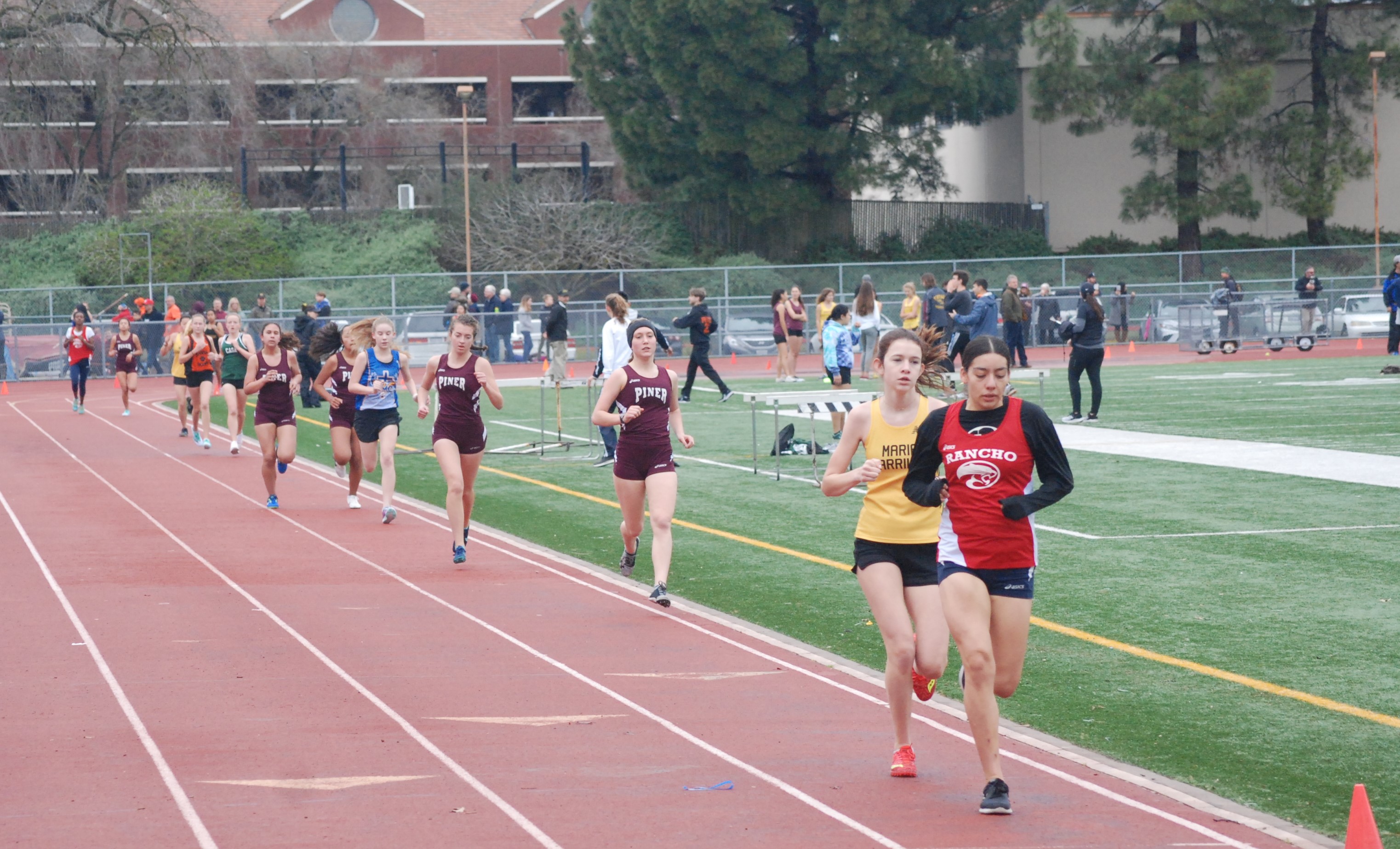 Athlete prepares for pole vault on a track with others watching.