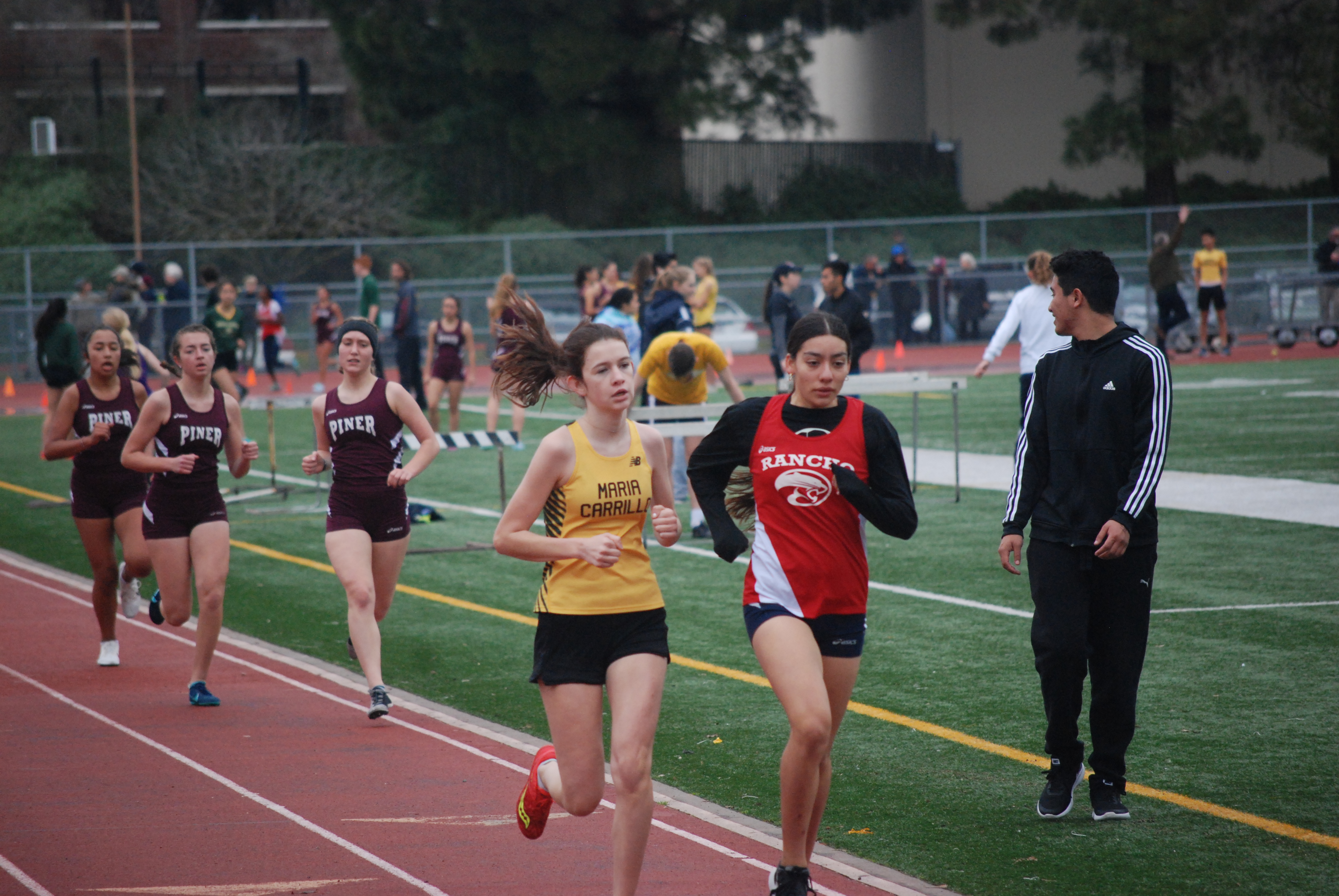Athlete prepares for pole vault on a track with others watching.