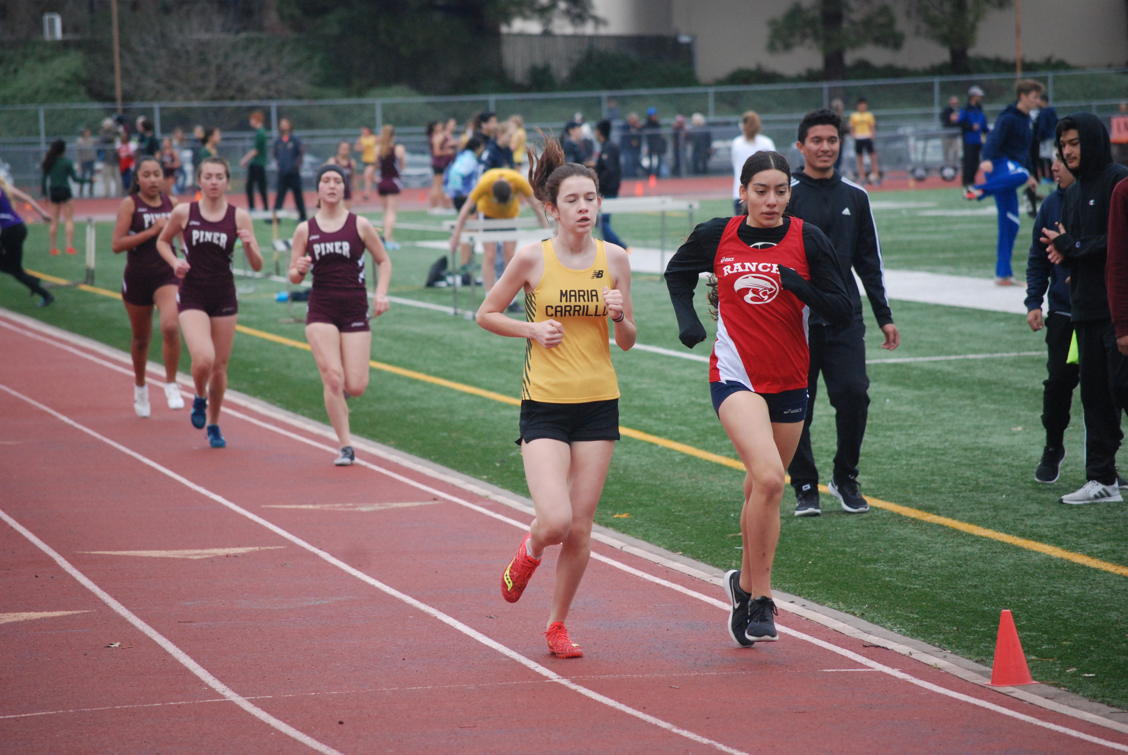 Athlete prepares for pole vault on a track with others watching.