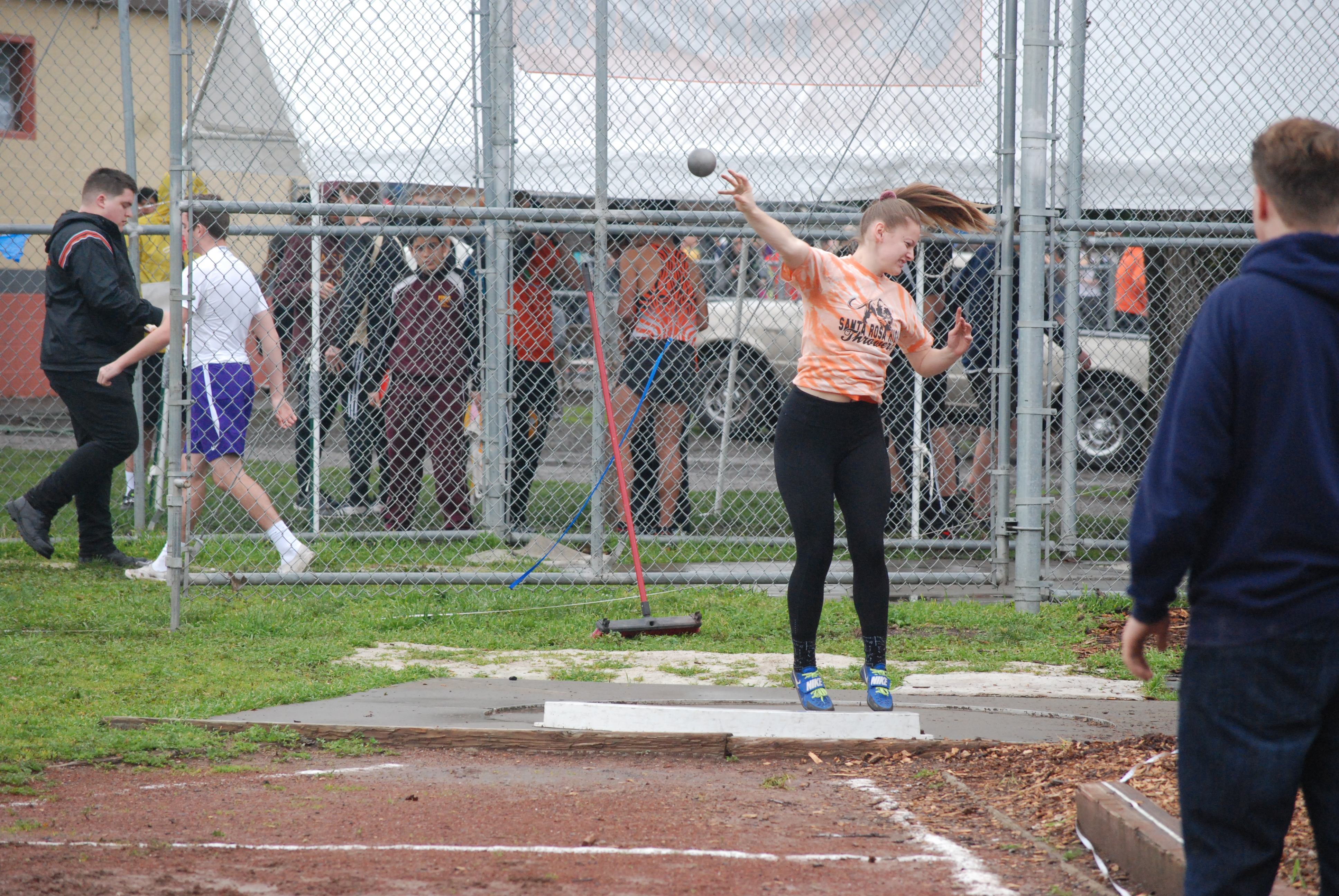 Athlete prepares for pole vault on a track with others watching.