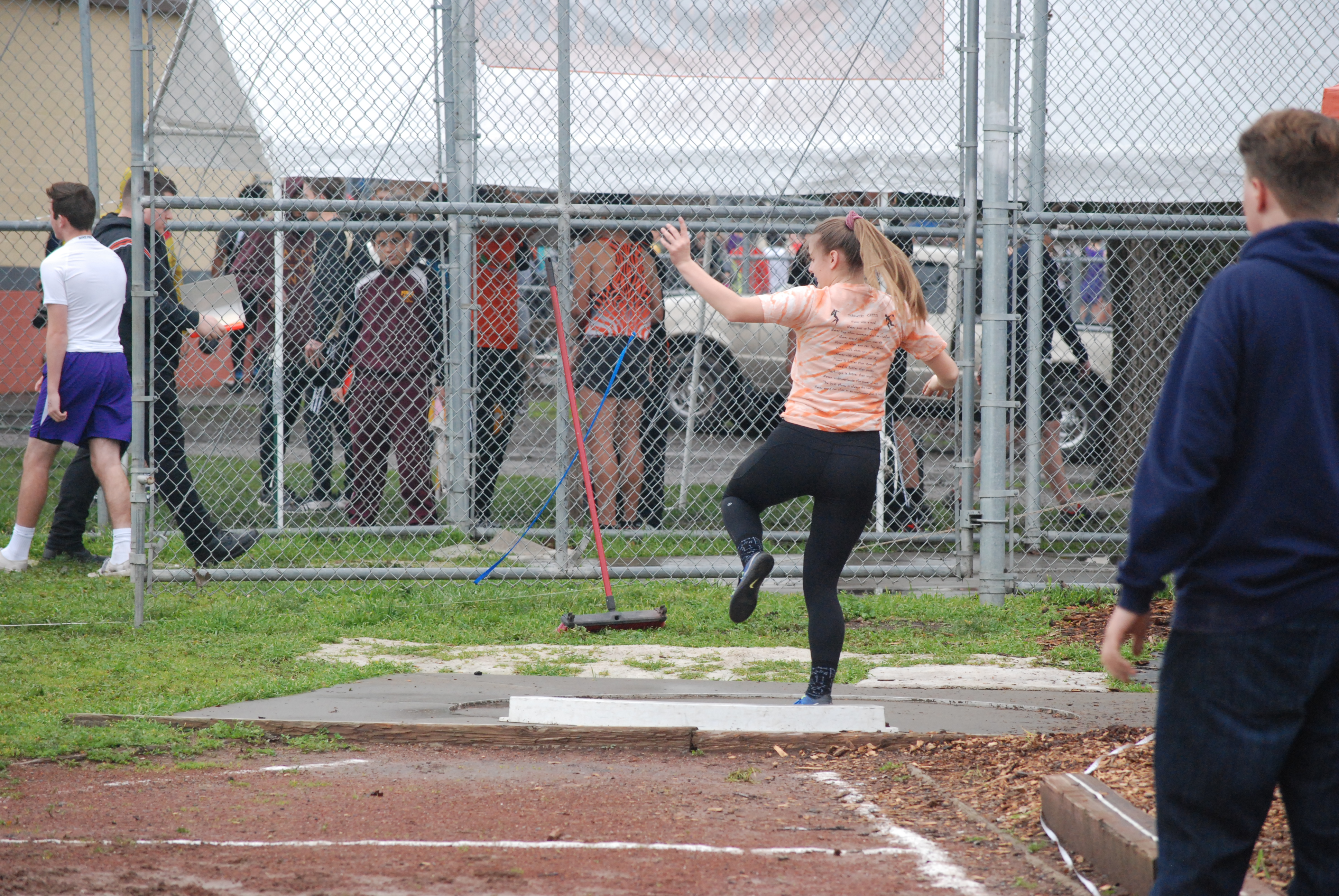 Athlete prepares for pole vault on a track with others watching.