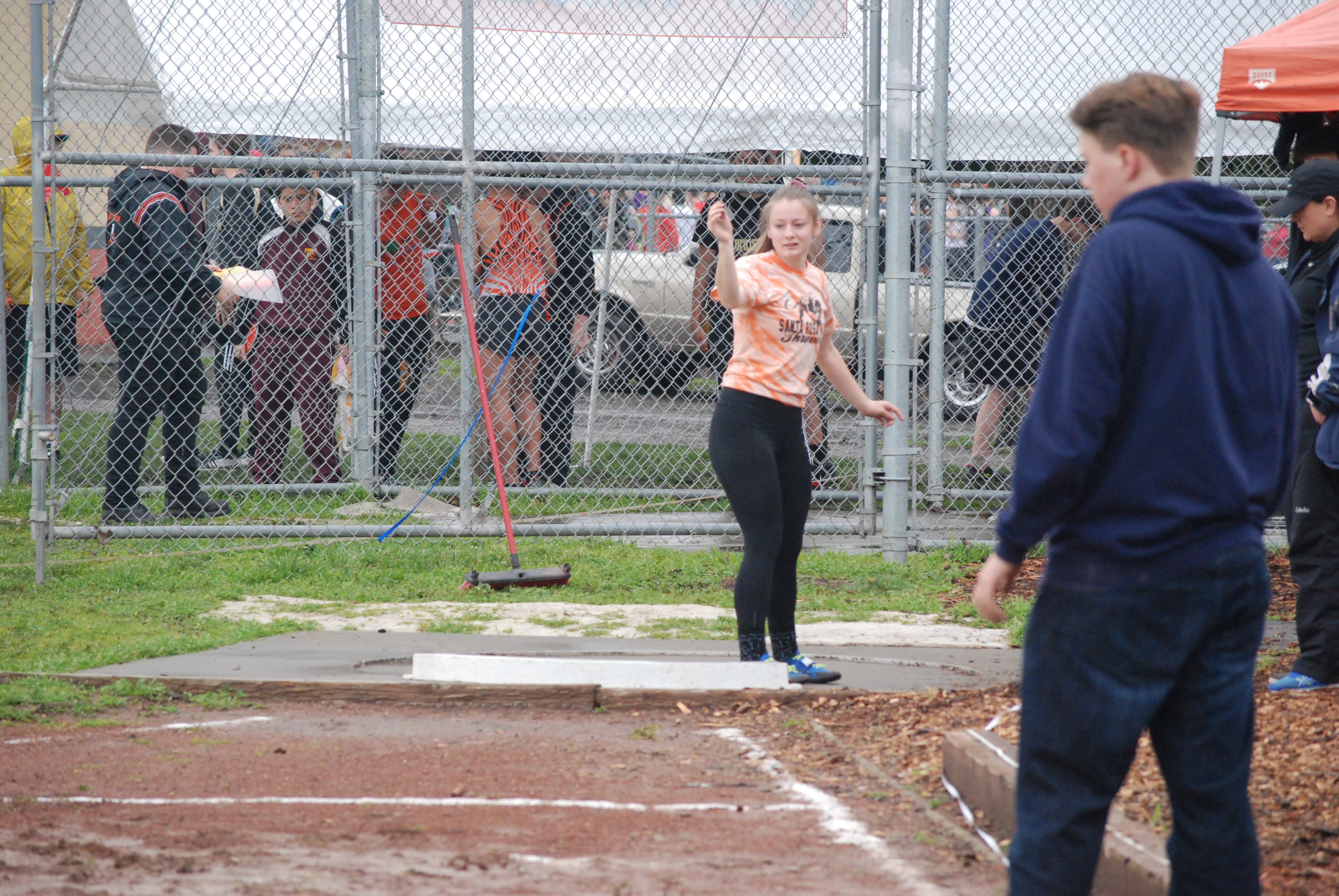 Athlete prepares for pole vault on a track with others watching.