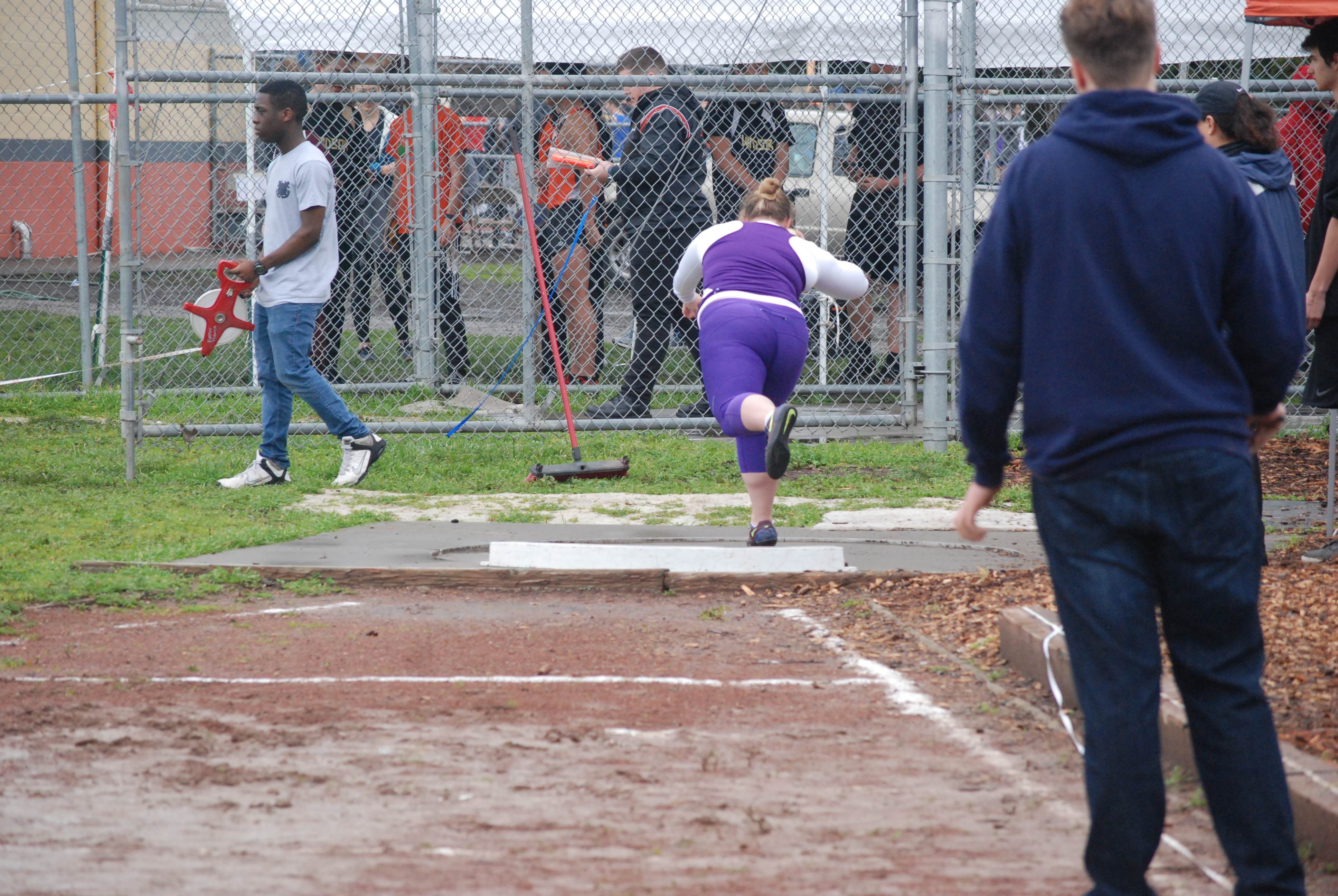 Athlete prepares for pole vault on a track with others watching.