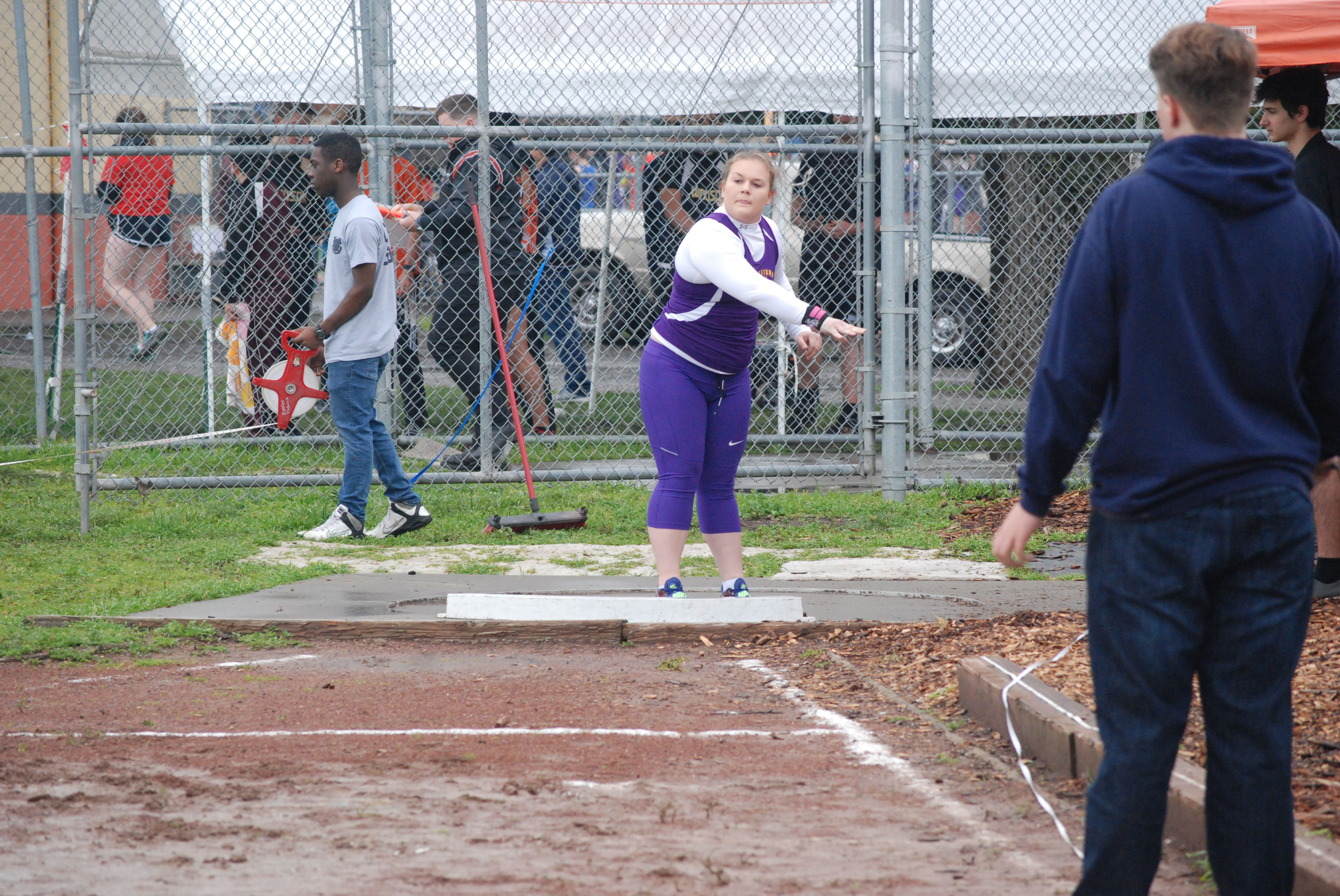 Athlete prepares for pole vault on a track with others watching.