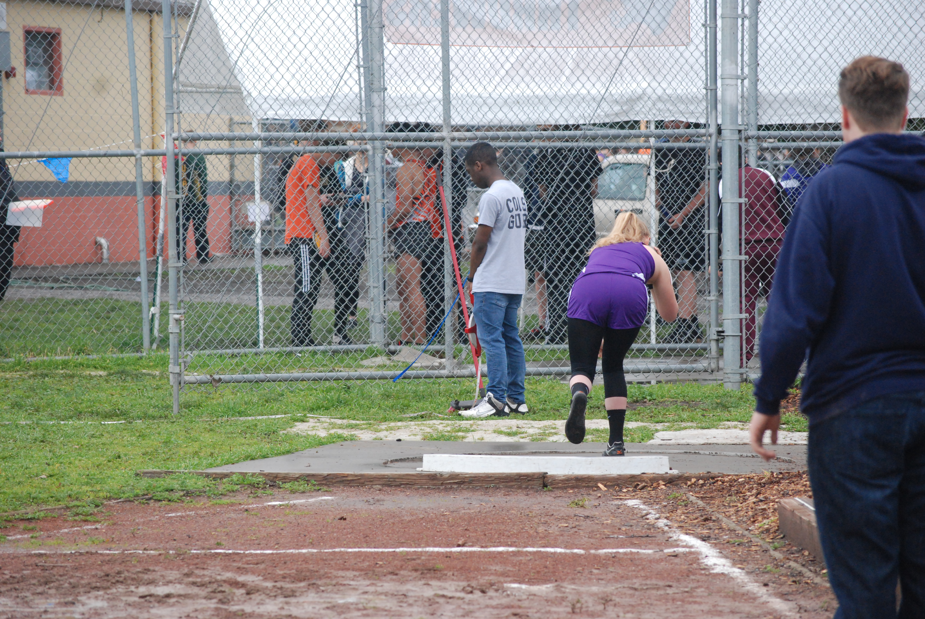 Athlete prepares for pole vault on a track with others watching.