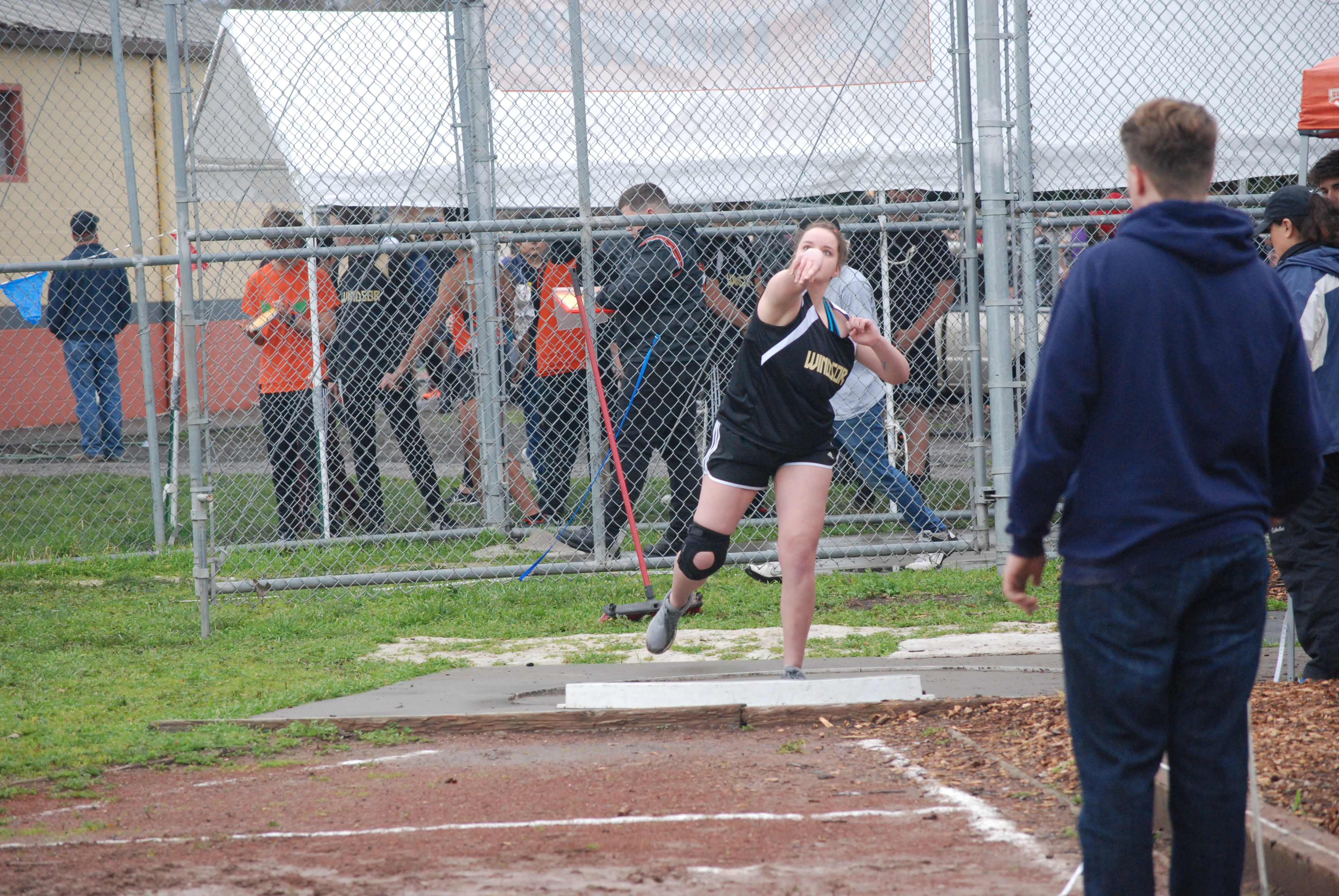 Athlete prepares for pole vault on a track with others watching.