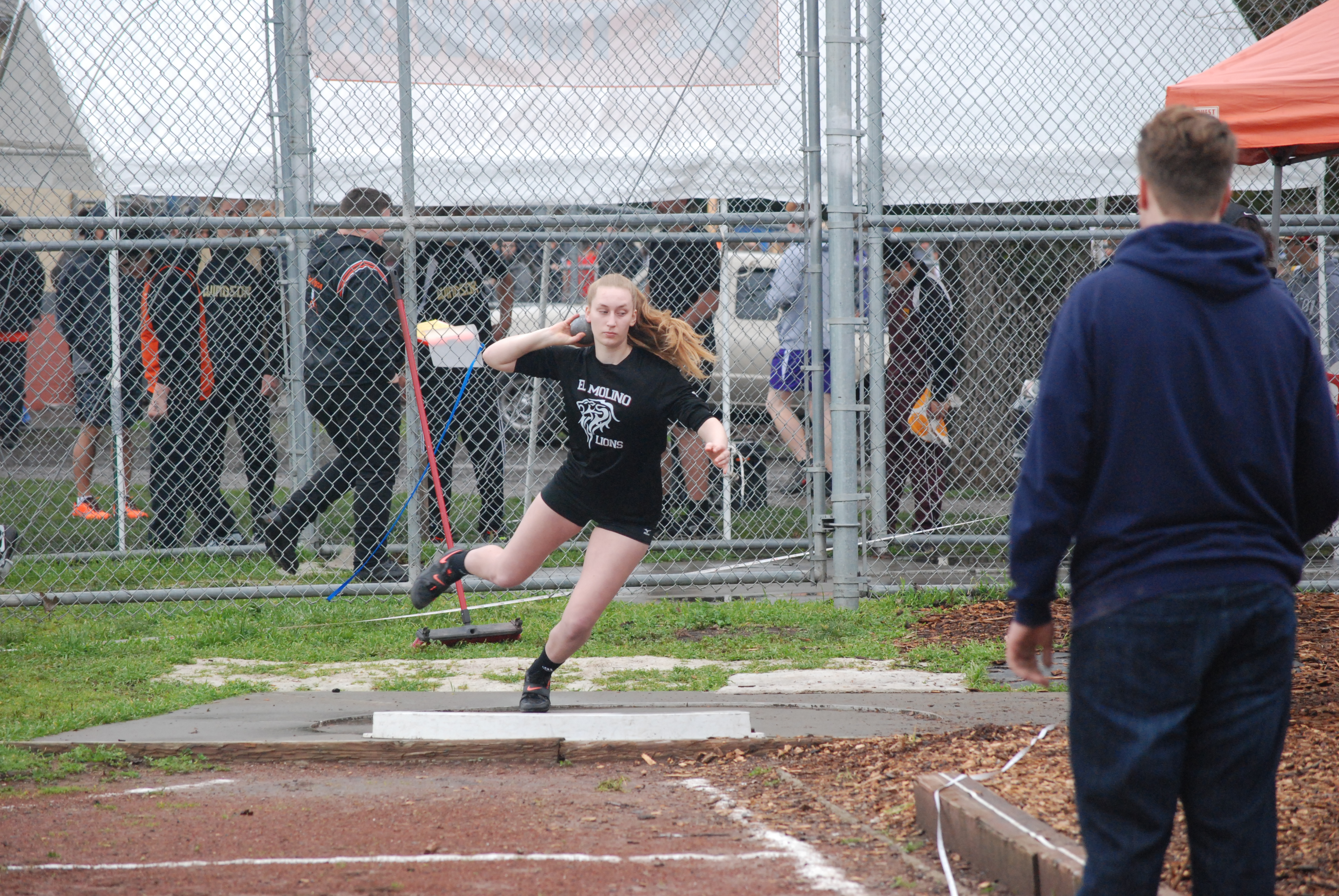 Athlete prepares for pole vault on a track with others watching.