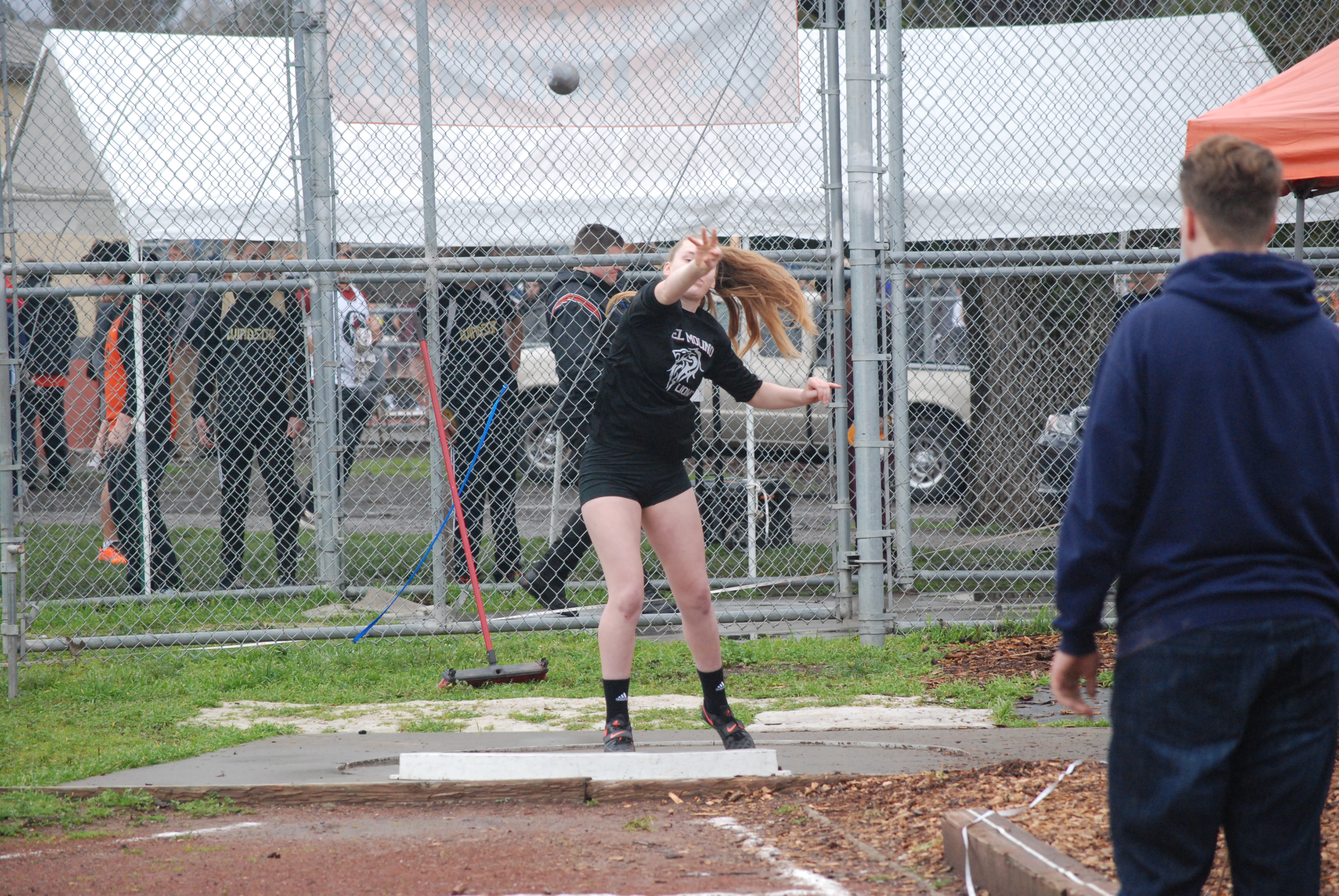 Athlete prepares for pole vault on a track with others watching.